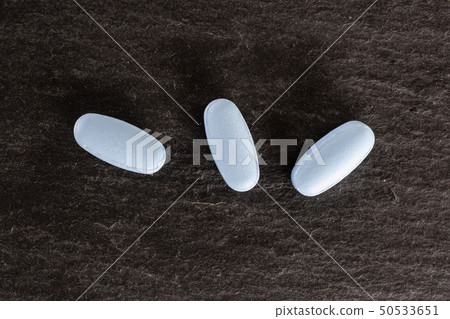 Blue medical pills on grey stone 50533651