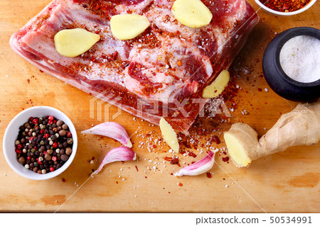 Raw fresh meat, uncooked lamb or beef ribs with pepper, garlic, salt and spices on dark stone 50534991