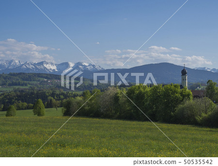 Beautiful spring rural mountain landscape in the Bavarian Alps with church village and snow covered Beautiful spring rural mountain landscape in the Bavarian Alps with church village and snow covered 50535542