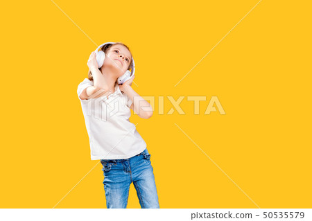 Girl listening to music in wireless headphones on yellow background . Dancing girl. Happy small girl 50535579