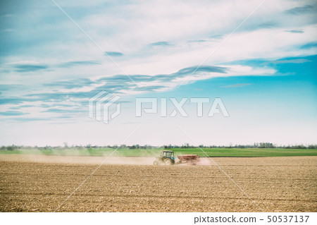 Tractor with Seeder In Dusty Field In Spring Season. Beginning Of Agricultural Spring Season Tractor with Seeder In Dusty Field In Spring Season. Beginning Of Agricultural Spring Season 50537137