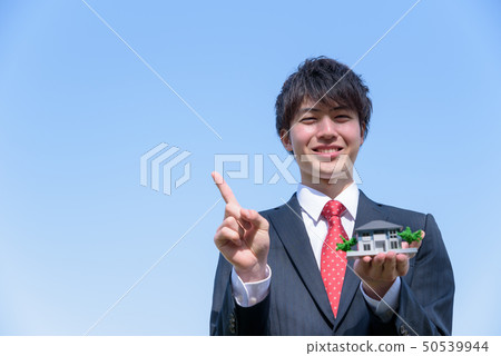 A businessman with a house model A businessman with a house model 50539944