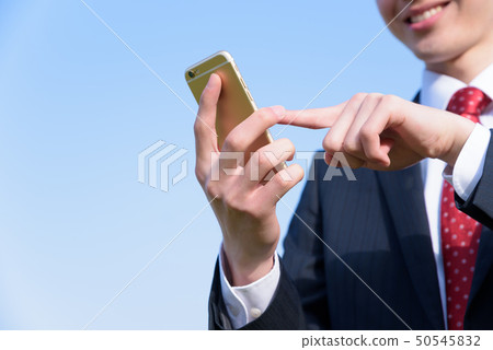 A businessman operating a smartphone A businessman operating a smartphone 50545832