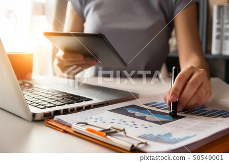 Women use the tablet and work papers at the table. Women use the tablet and work papers at the table. 50549001