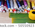 Colorful thread for sewing on wood background 50550923