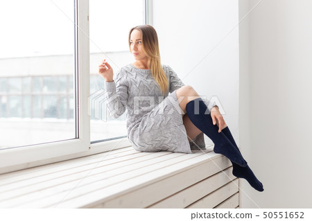 People and fashion concept - Gorgeous romantic woman in wool dress sitting on the window sill 50551652