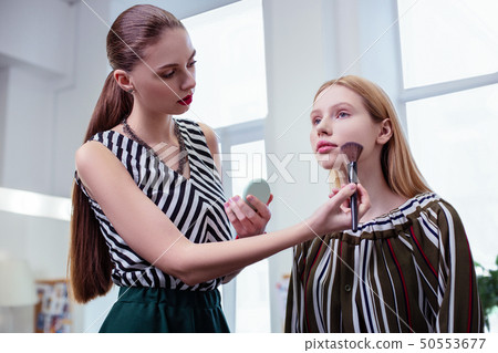 Nice long haired visagiste applying facial powder Nice long haired visagiste applying facial powder 50553677