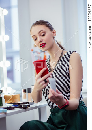Joyful young woman holding her red smartphone 50554277