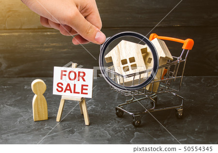 Magnifying glass is looking at cart with houses 50554345