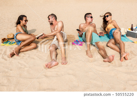 Group of friends lying at the beach taking sunbath 50555220