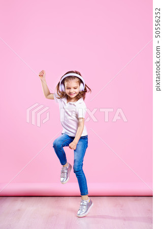 Girl listening to music in headphones on pink background. Dancing girl. Happy small girl dancing to Girl listening to music in headphones on pink background. Dancing girl. Happy small girl dancing to 50556252