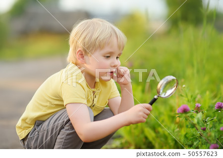 Kid exploring nature with magnifying glass. Kid exploring nature with magnifying glass. 50557623