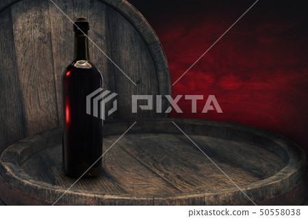 Red wine bottle on a old barrel table background 50558038