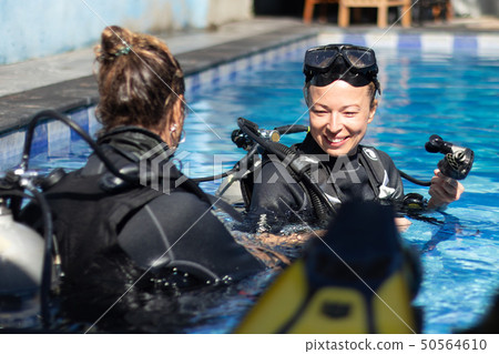 Woman getting first experience with scuba diving under the guidance of experienced recreational 50564610
