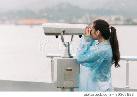 tourist looking through coin operated binoculars 50565658