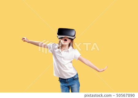 Girl 7 y.o in formal outfit wearing VR glasses putting hands out in excitement isolated on yellow Girl 7 y.o in formal outfit wearing VR glasses putting hands out in excitement isolated on yellow 50567890