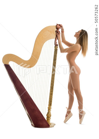 Naked woman in ballet shoes standing near harp 50573262