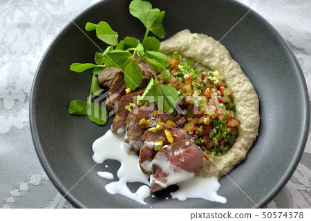 Roasted lamb with hummus, table salad and yoghurt sauce Roasted lamb with hummus, table salad and yoghurt sauce 50574378