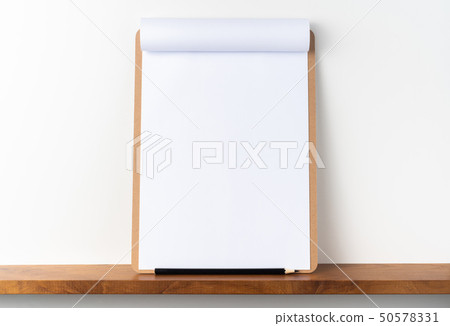 white flipped paper on clipboard on bookshelf 50578331