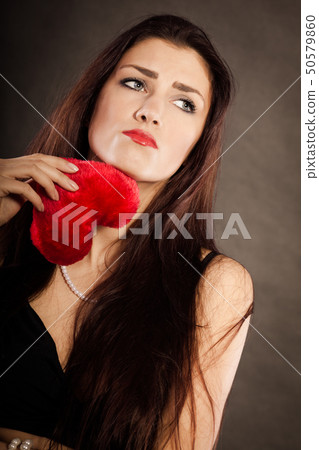 Sad lovely woman holds red heart on black Sad lovely woman holds red heart on black 50579860