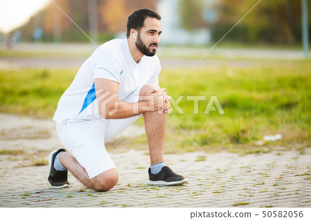 Leg Injury. Male athlete suffering from pain in leg while exercising outdoors 50582056