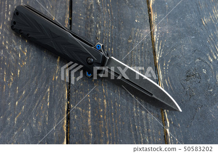 Black knife wooden background. Black texture. 50583202