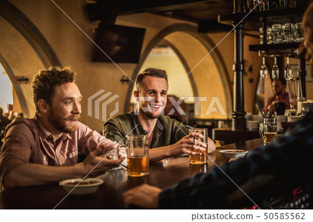 Cheerful friends drinking draft beer in a pub Cheerful friends drinking draft beer in a pub 50585562