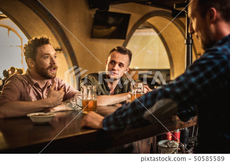 Cheerful friends drinking draft beer in a pub Cheerful friends drinking draft beer in a pub 50585589