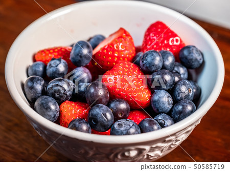 Strawberries and blueberries in white bowl ready to eat Strawberries and blueberries in white bowl ready to eat 50585719