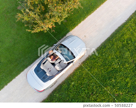 Aerial view of successful man driving and enjoying his silver convertible luxury sports car on the 50588227