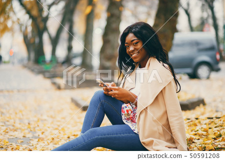 Black woman sitting in a autumn city Black woman sitting in a autumn city 50591208