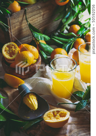 Table with box of fresh orange with orange tree branch and fresh orange juice Table with box of fresh orange with orange tree branch and fresh orange juice 50592056