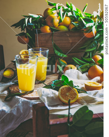 Table with box of fresh orange with orange tree branch and fresh orange juice Table with box of fresh orange with orange tree branch and fresh orange juice 50592067
