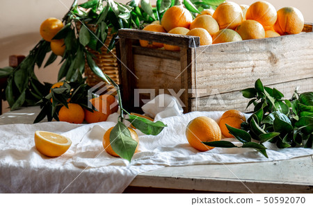 Table with box of fresh orange with orange tree branch and fresh orange juice 50592070