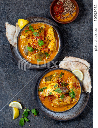 INDIAN FOOD. Traditional KERALA FISH CURRY with naan bread, gray plate, black background  50592081