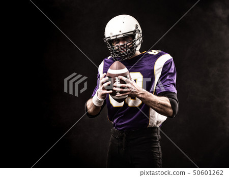 American football player holding the ball in his hands. Black background, copy space. The concept of 50601262