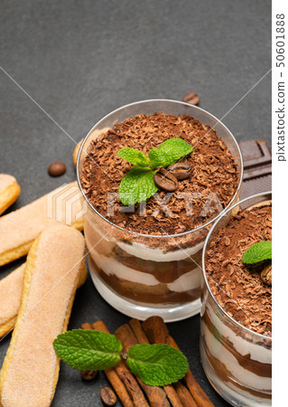 Classic tiramisu dessert in a glass and savoiardi cookies on dark concrete background 50601888