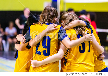 Female volleyball players huddling together before Female volleyball players huddling together before 50604902