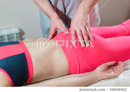 Close-up of a young girl's spine base editing by a male physiotherapist of visceral massage. The Close-up of a young girl's spine base editing by a male physiotherapist of visceral massage. The 50606982