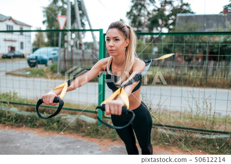 Beautiful female athlete, girl wrung on loops, gymnastics, muscle stretching, flexibility and 50612214