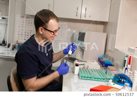 laboratory assistant analyzing a blood sample laboratory assistant analyzing a blood sample 50612537