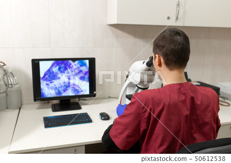 Young scientist looking through a microscope in a Young scientist looking through a microscope in a 50612538