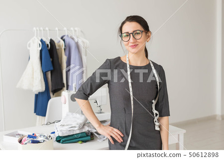 Dressmaker, fashion designer and tailor concept - Young dressmaker woman over clothes rack with Dressmaker, fashion designer and tailor concept - Young dressmaker woman over clothes rack with 50612898