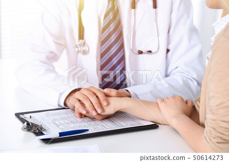 Hand of doctor  reassuring her female patient. Concepts of medical ethics and trust in medicine 50614273