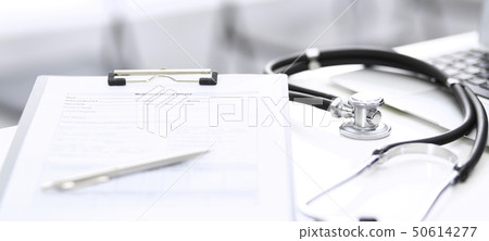 Stethoscope, clipboard with medical form lying on hospital reception desk with laptop computer and Stethoscope, clipboard with medical form lying on hospital reception desk with laptop computer and 50614277