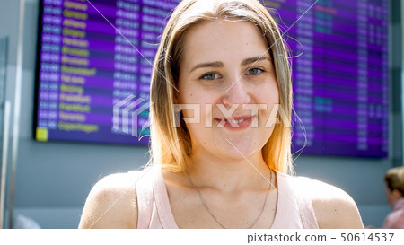 Portrait of smiling young woman waiting fro flight in international airport terminal Portrait of smiling young woman waiting fro flight in international airport terminal 50614537