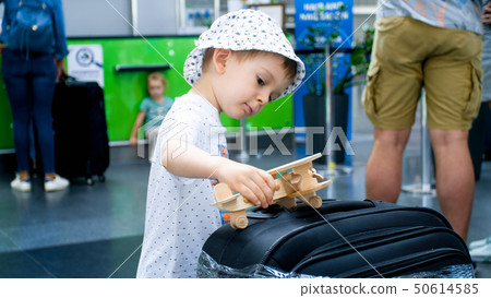 Portrait of little toddler boy playing with wooden airplane while waiting for flight in airport 50614585