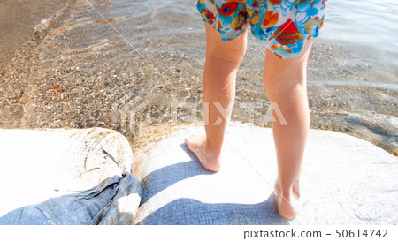 Closeup photo of little childs feet walking on the wet sand at sea beach Closeup photo of little childs feet walking on the wet sand at sea beach 50614742
