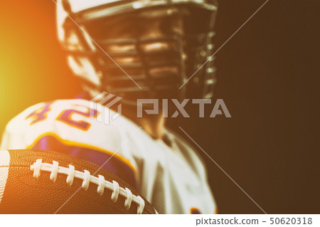 American football player holding the ball in his hands in front of the camera. Concept American American football player holding the ball in his hands in front of the camera. Concept American 50620318