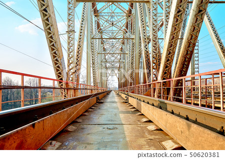 Reliable railway bridge, against the backdrop of beautiful nature and blue sky. Looking through the 50620381